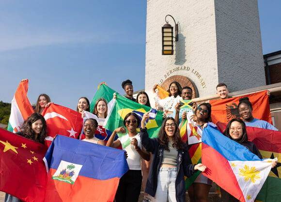 International students take a photo in front of the clocktower holding their country flags